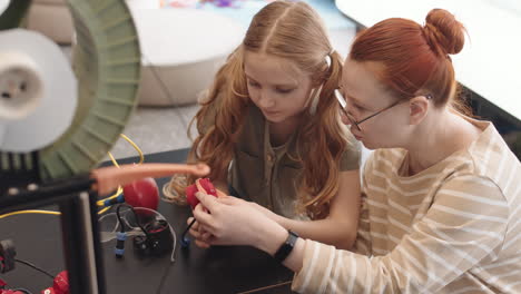female teacher and intelligent teenage girl building robot