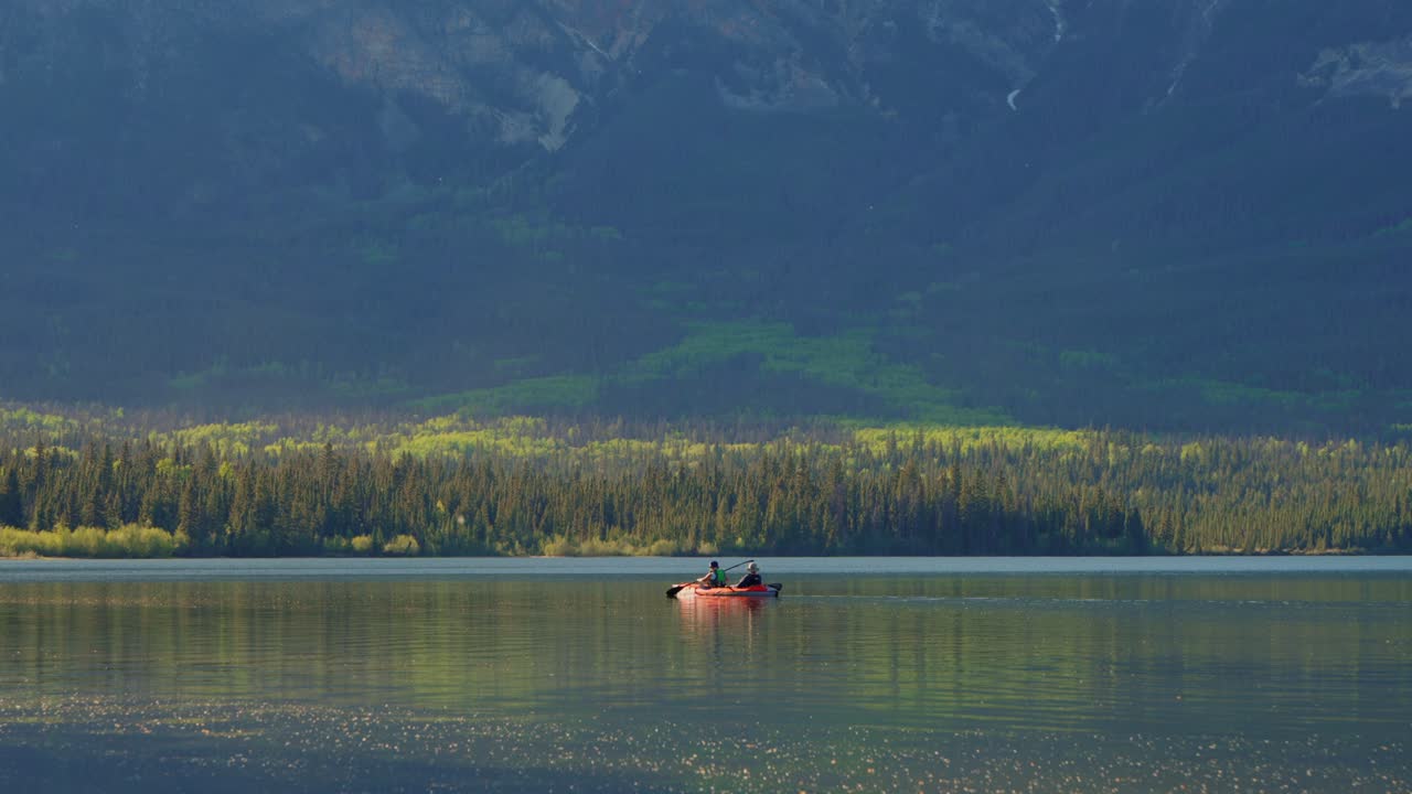 Zwei Personen genießen malerisches Kajakfahren auf dem Pyramid Lake, der Berge und Wald im Jasper Nationalpark, Kanada, widerspiegelt.