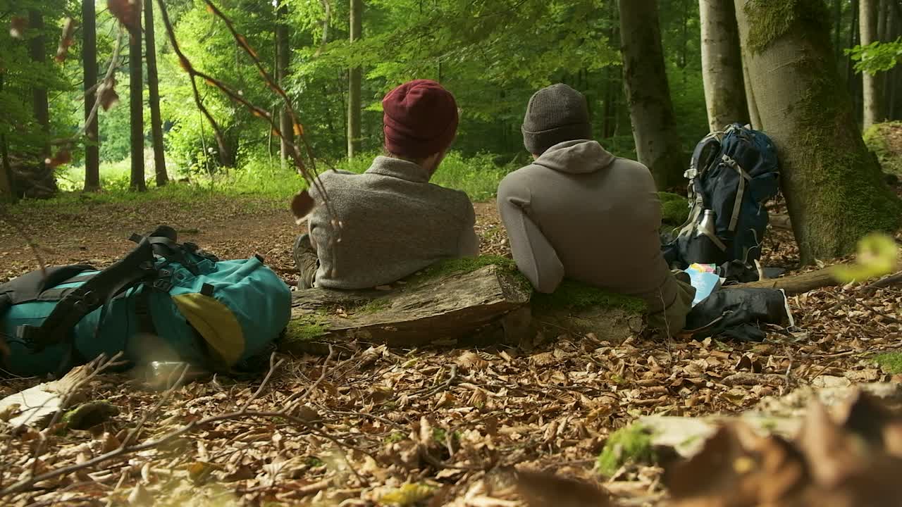 A perfect visual for stories about escaping the hustle and bustle. Two people sit in comfortable silence, finding peace and quiet in a lush, green woodland