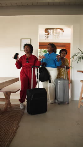 vertical video: african american women arriving with luggage, laughing and enjoying holiday reunion