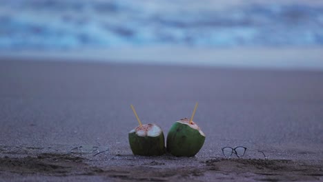 two coconut kept on the beach with blurred waves on the background