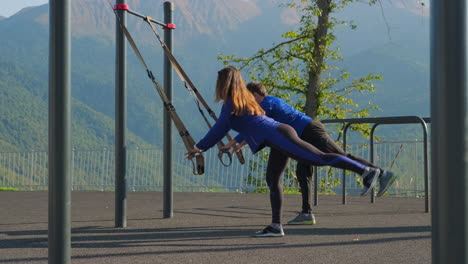 pareja trabajando al aire libre con bandas de resistencia en un pintoresco lugar de montaña