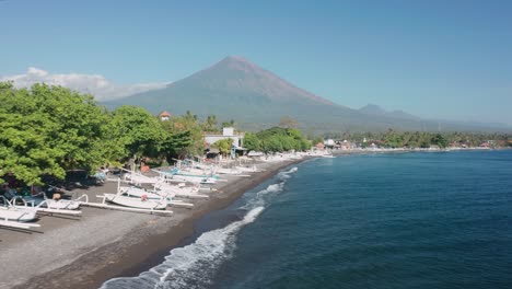 amed beach with traditional white jukung outrigger boats, mount agung, aerial