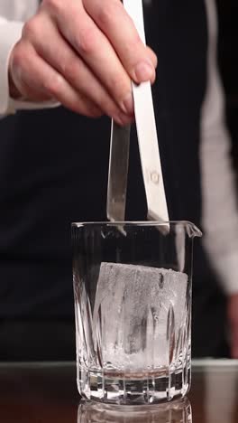 bartender adding ice to a cocktail glass
