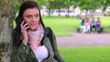 Student-leaning-against-a-tree-making-a-phone-call