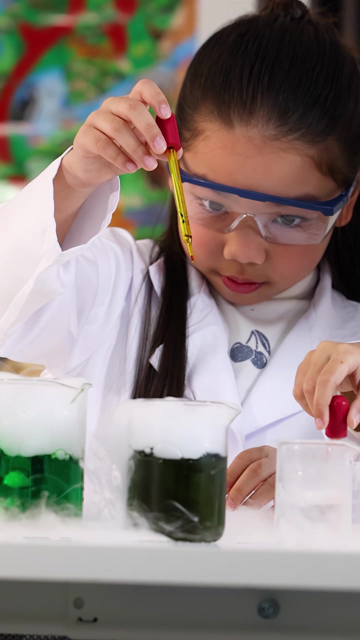 Gadis Asia mengenakan kacamata pengaman menggunakan pipet untuk eksperimen kimia di laboratorium yang terang.