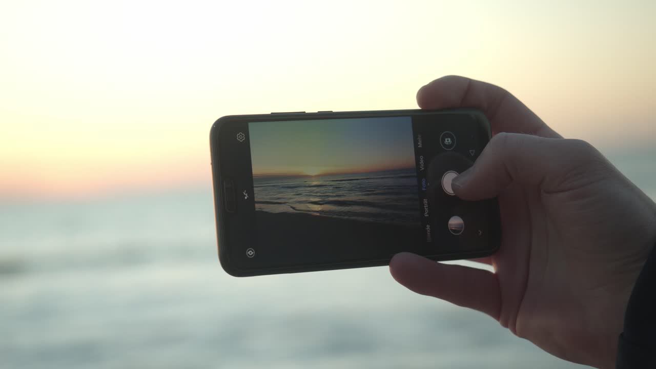 persona captura la puesta de sol de sylt con su teléfono móvil.