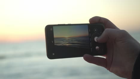 person captures the sunset of sylt with his mobile phone