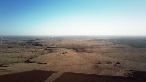 Epic-aerial-pull-back-through-the-propellers-of-a-giant-wind-turbine-on-a-wind-farm-in-Texas-on-a-clear-day