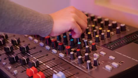 hand adjusting audio mixer controls in a recording studio