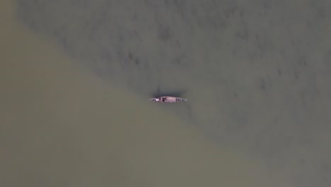 Aerial-View-Of-Lone-Fisherman-On-Traditional-Wooden-Boat-On-River