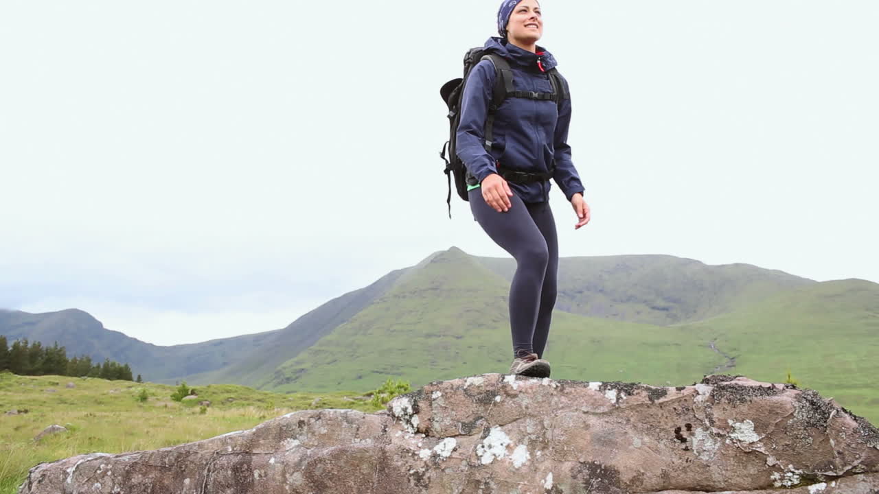정상에 도달하고 주변을 둘러보는 건강한 여성