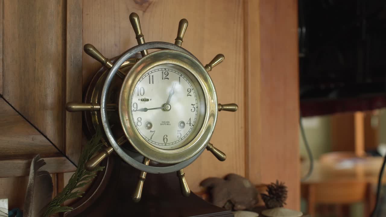 A Vintage Clock Shaped Like a Ship’s Wheel Hangs on a Wooden Wall - Close Up