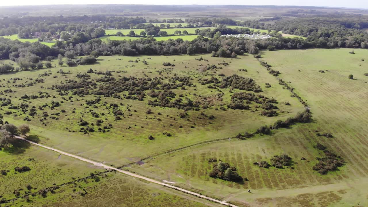 Aerial view of a lush green landscape with forests and open fields. push forward