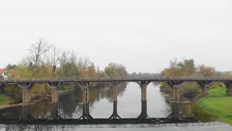 perfect symmetrical water reflection of wooden bridge on river, aerial