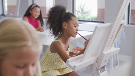 video of focused diverse girls painting during art lessons at school