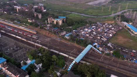 Aerial-View-of-Railway-Station-with-Trains-Passing-By-in-Vasai,-Mumbai,-India---drone-shot