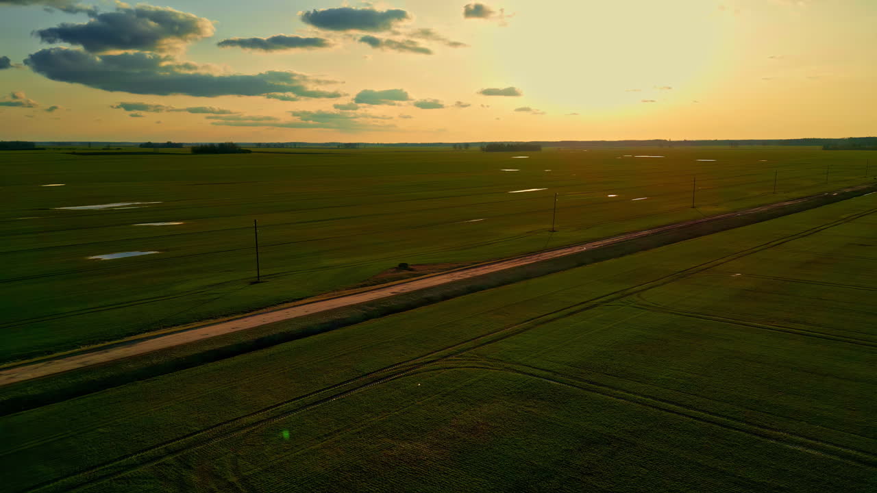 Drone footage of agricultural landscape with brightly lit sky and cloudscape in the background