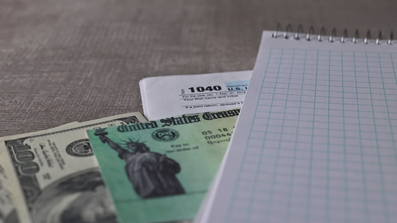 formulario de impuestos 1040 con cheque de reembolso y moneda billetes de dólar estadounidense de primer plano