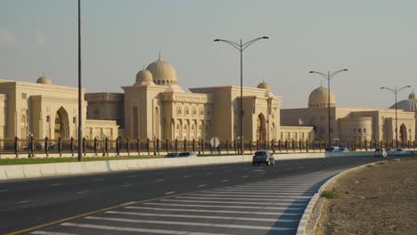 Vista-De-Los-Edificios-De-La-Universidad-Al-Qasimia-En-Sharjah,-Emiratos-árabes-Unidos-Con-Vehículos-Circulando-Por-La-Carretera---Toma-Panorámica