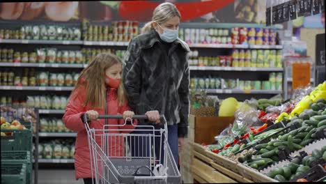 a mother and daughter with a shopping cart walk around the store and choose products. they look at prices and vegetables on the counter.