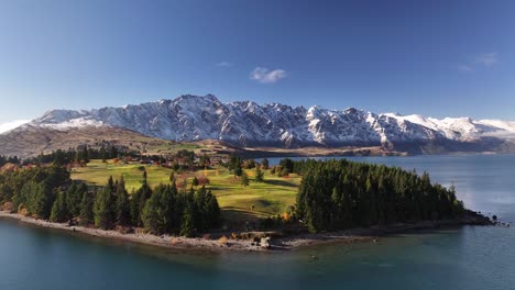 lush green golf course on peninsula in contrast to massive mountain range