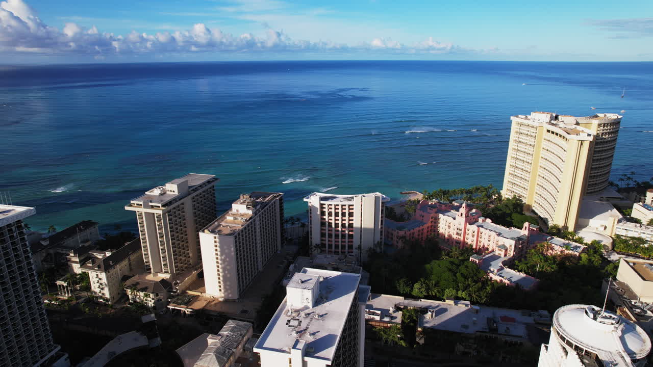Slow pan right to left of resorts on Waikiki beach on Oahu Hawaii with blue ocean water - Aerial view