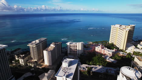 panorámica lenta de derecha a izquierda de los resorts en la playa de waikiki en oahu hawaii con agua azul del océano - vista aérea