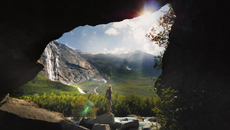 um viajante fica em um vale fabulosamente bonito entre montanhas altas e cachoeiras vistas através