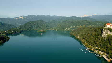 serene water on bled lake reflects blue sky and mountains, slovenia, drone