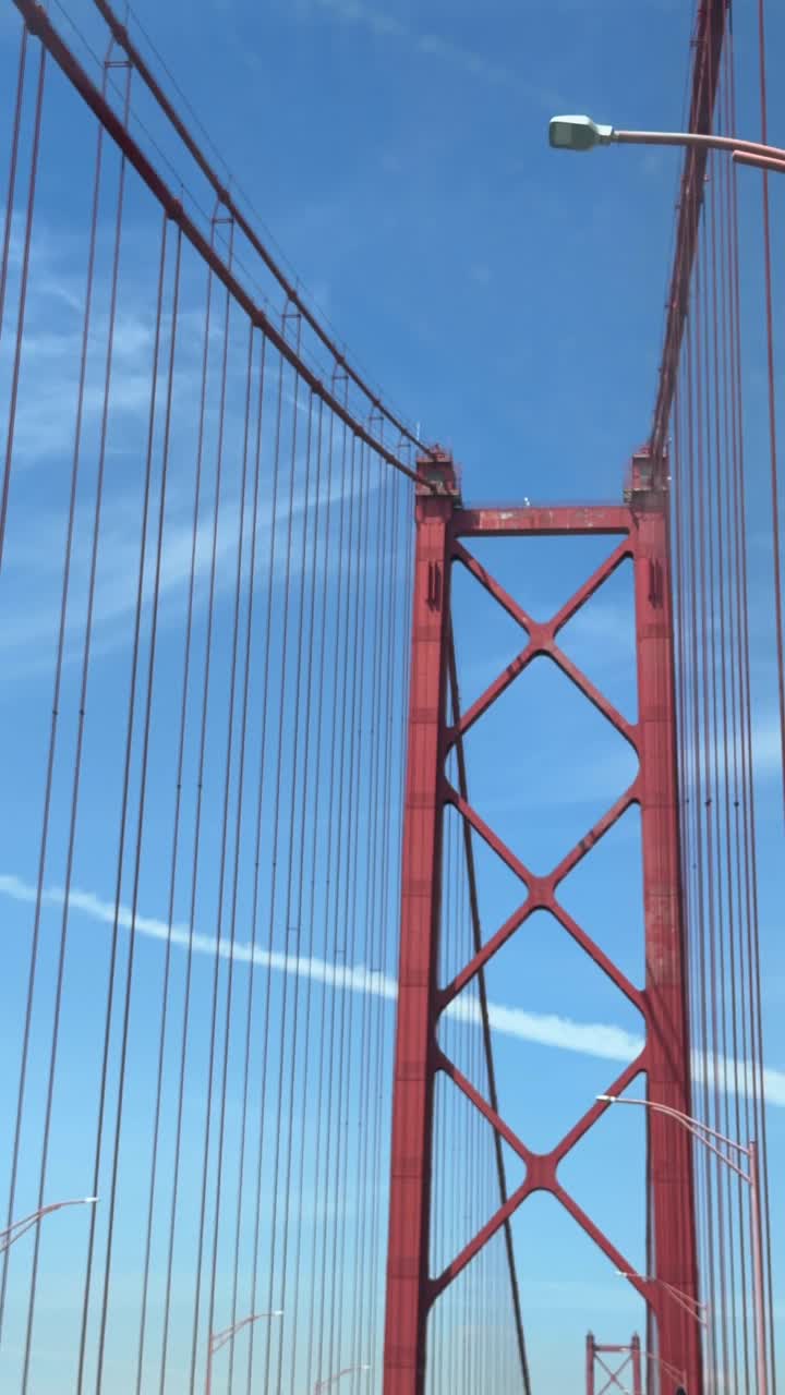 Driving Under a Red Suspension Bridge Tower and Cables