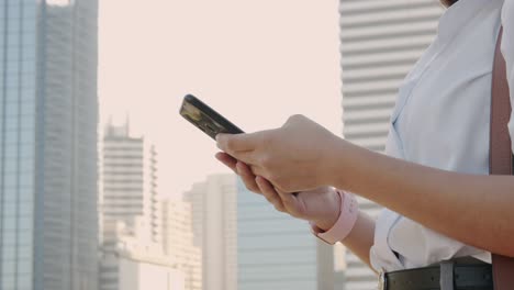 side view of young business woman while standing using smartphone in the city. close- up of hand young women touch mobile digital