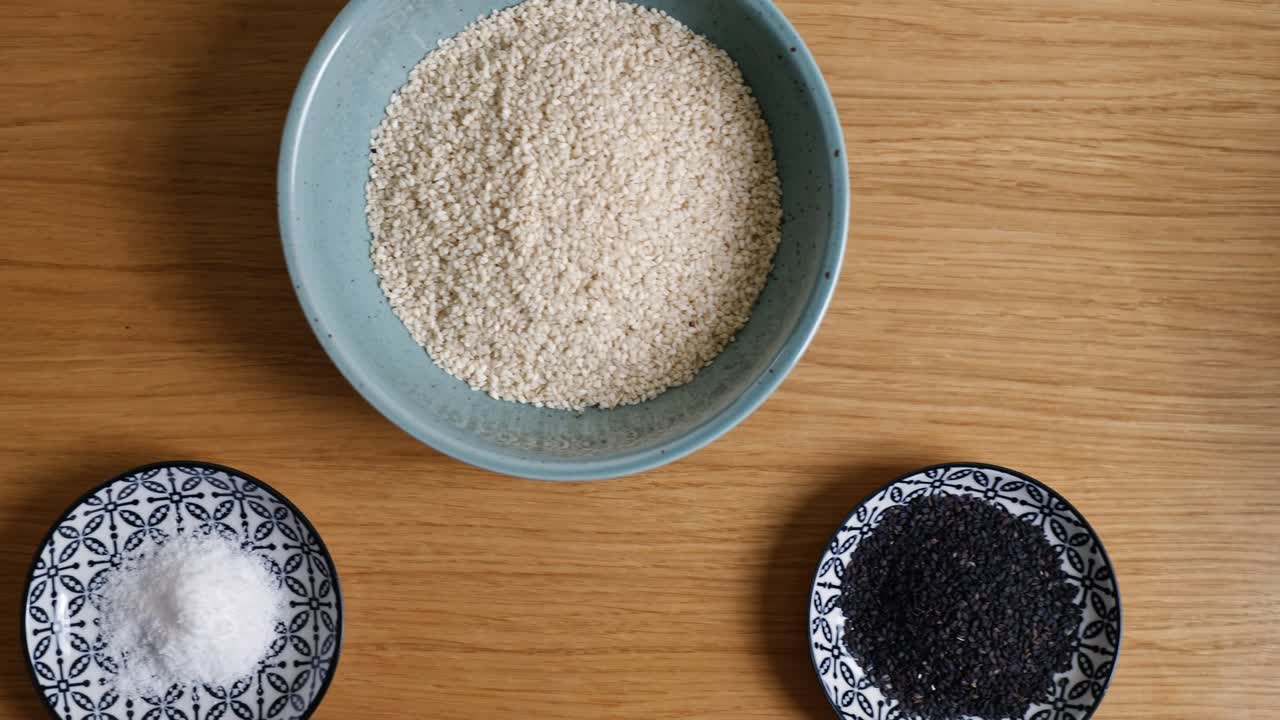 Dolly shot of sesame bowls and a strainer on a wooden countertop