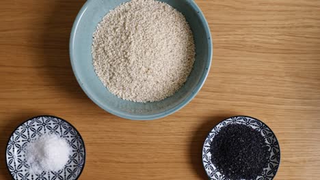dolly shot of sesame bowls and a strainer on a wooden countertop