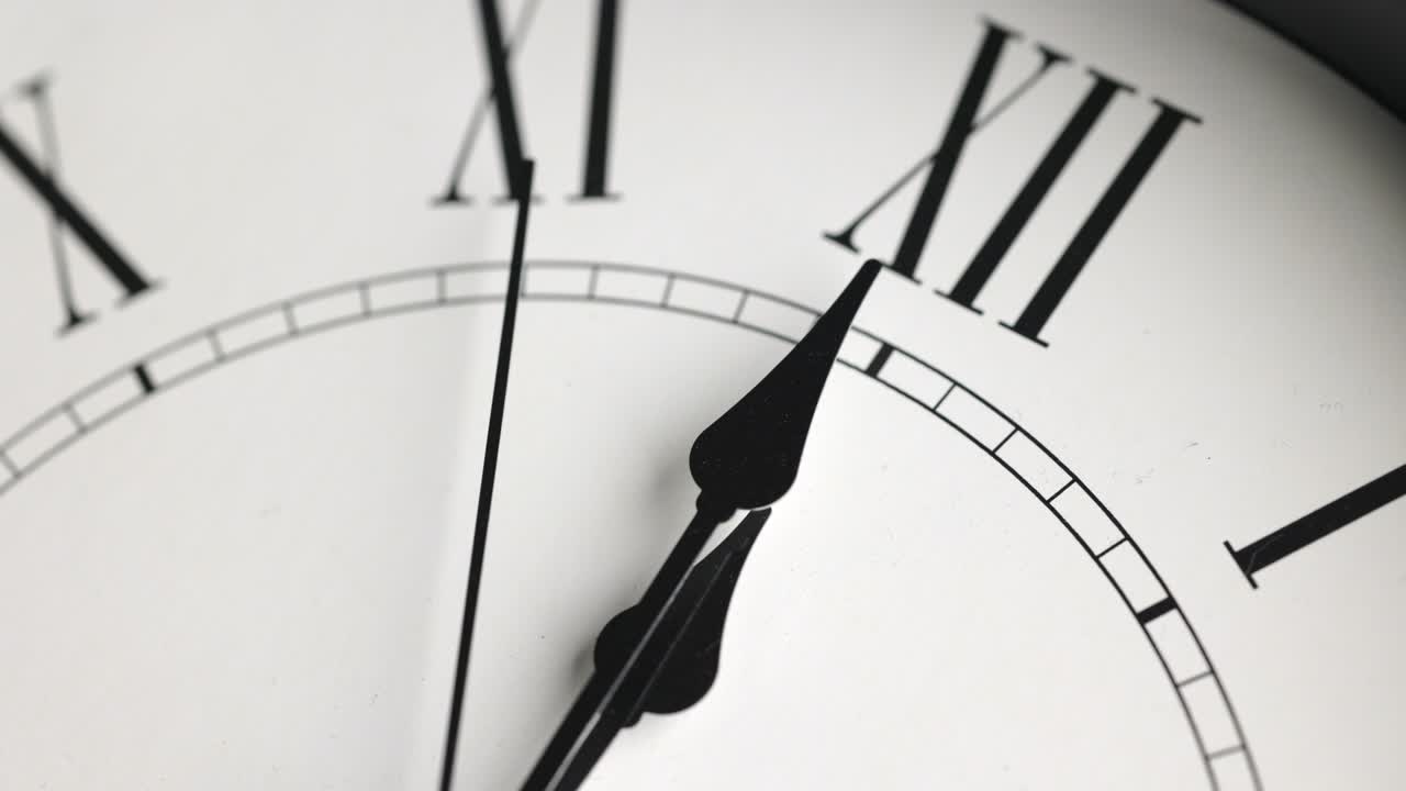 Filmato in time-lapse. Grande orologio da parete bianco. Imposta l'ora alle 12:00. La lancetta rossa dei minuti continua a girare. Numeri romani.