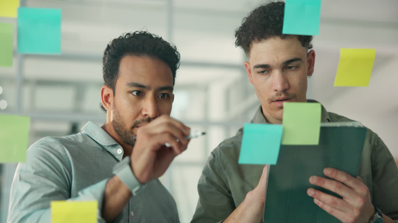 Two Businessmen Collaborating and Brainstorming Ideas on a Glass Board