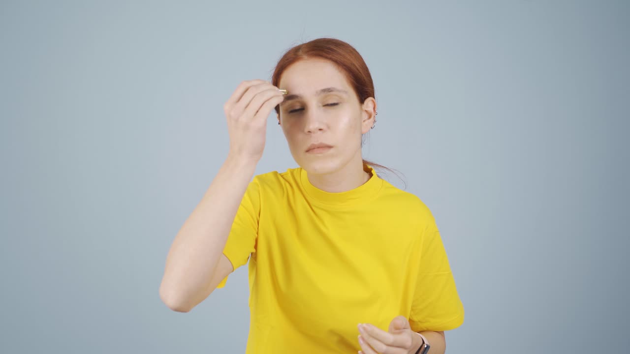 Woman plucking her eyebrows with tweezers. Facial care.