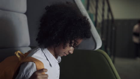 African-american-teen-girl-sitting-bench-close-up.-Schoolgirl-take-off-backpack.