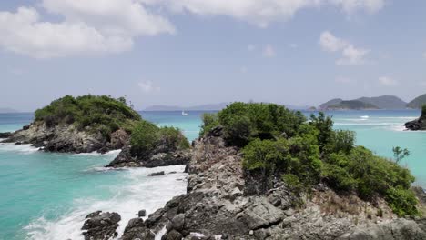 Drone-aerial-wide-view-passing-by-two-archipelagos-revealing-boat-in-distance-blue-sky-white-clouds-turquoise-water-relaxation-vacation-tourism