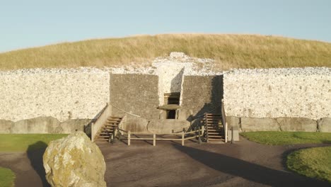 entrance passage and entrance stone of newgrange during sunrise in county meath, ireland. - aerial forward shot