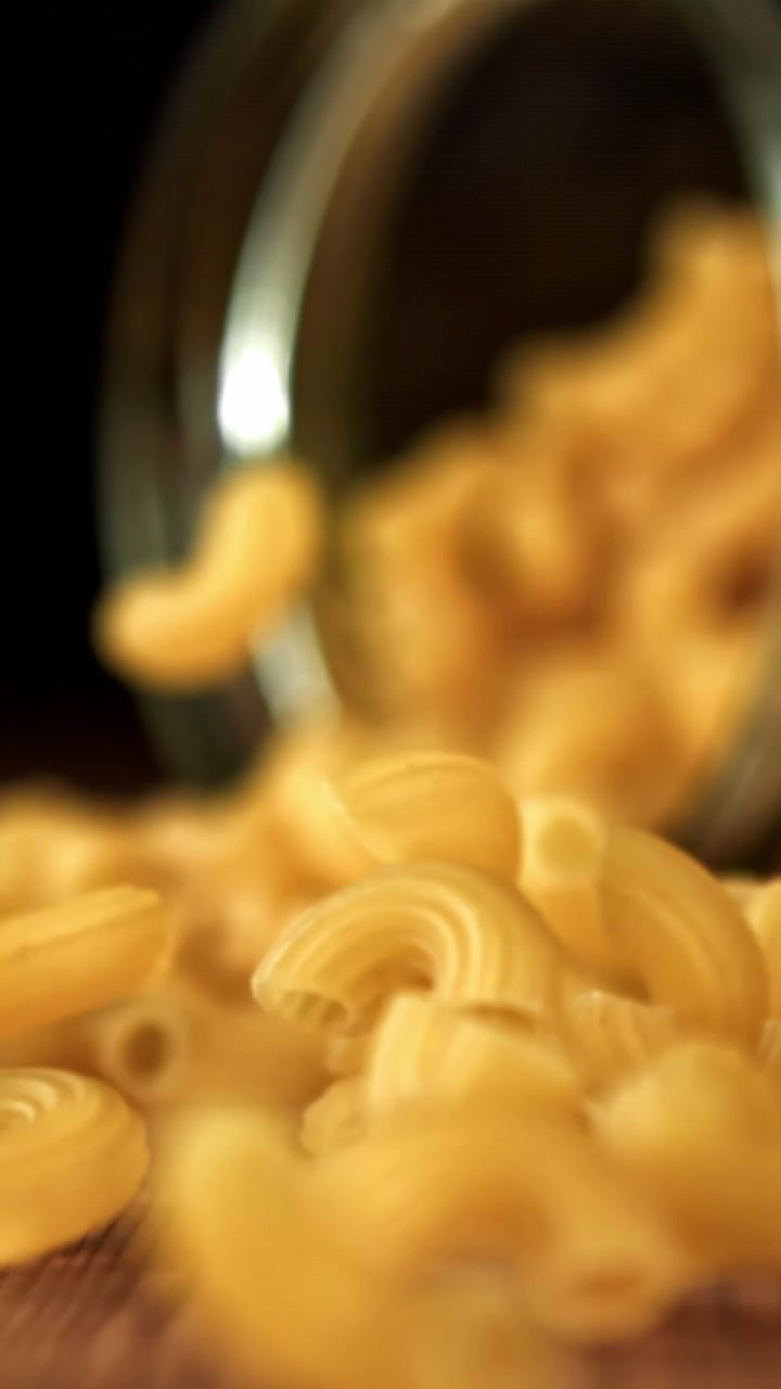 Maccheroni secchi che cadono su un tavolo di legno al rallentatore