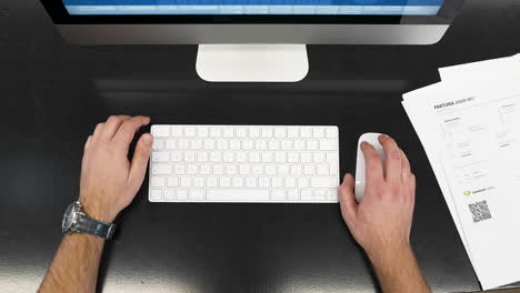 male hands working on a modern pc,typing,clicking,pushing away papers