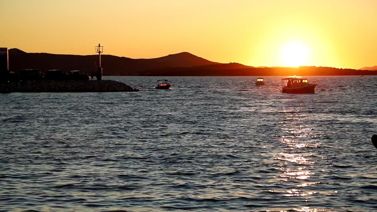 보트와 요트는 크로아티아 바이오그라드의 일몰 때 선착장에 들어가고 나옵니다.