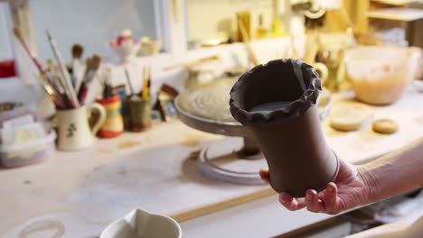 close up of male potter applying glaze to clay vase in ceramics studio