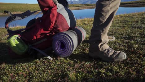 la mochila de viaje cae al suelo detrás de las piernas de pie del viajero, cierra