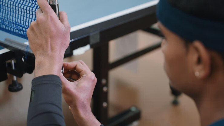Close up rear view of man tightening table tennis net indoors, focusing on preparation and accuracy before training, ensuring equipment setup is ready for competitive practice