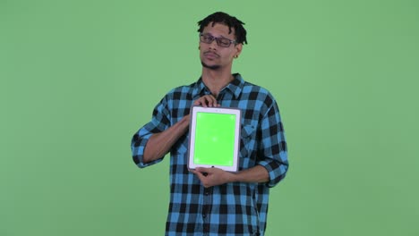 joven feliz y guapo hombre hipster africano mostrando una tableta digital