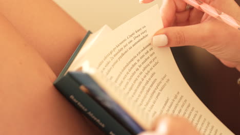 una persona que sostiene un libro abierto, leyendo, con el texto enfocado y el resto ligeramente borroso