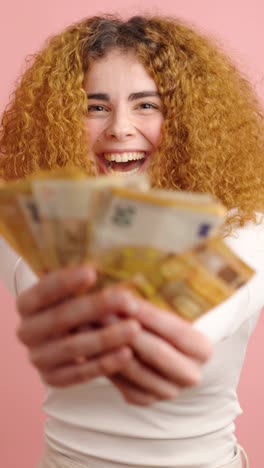 young woman showing banknotes on pink background