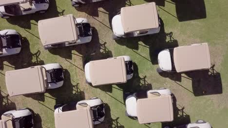 Close-Up-of-Golf-Buggy-Roofs-on-Green-Golf-Course,-Aerial-Shot